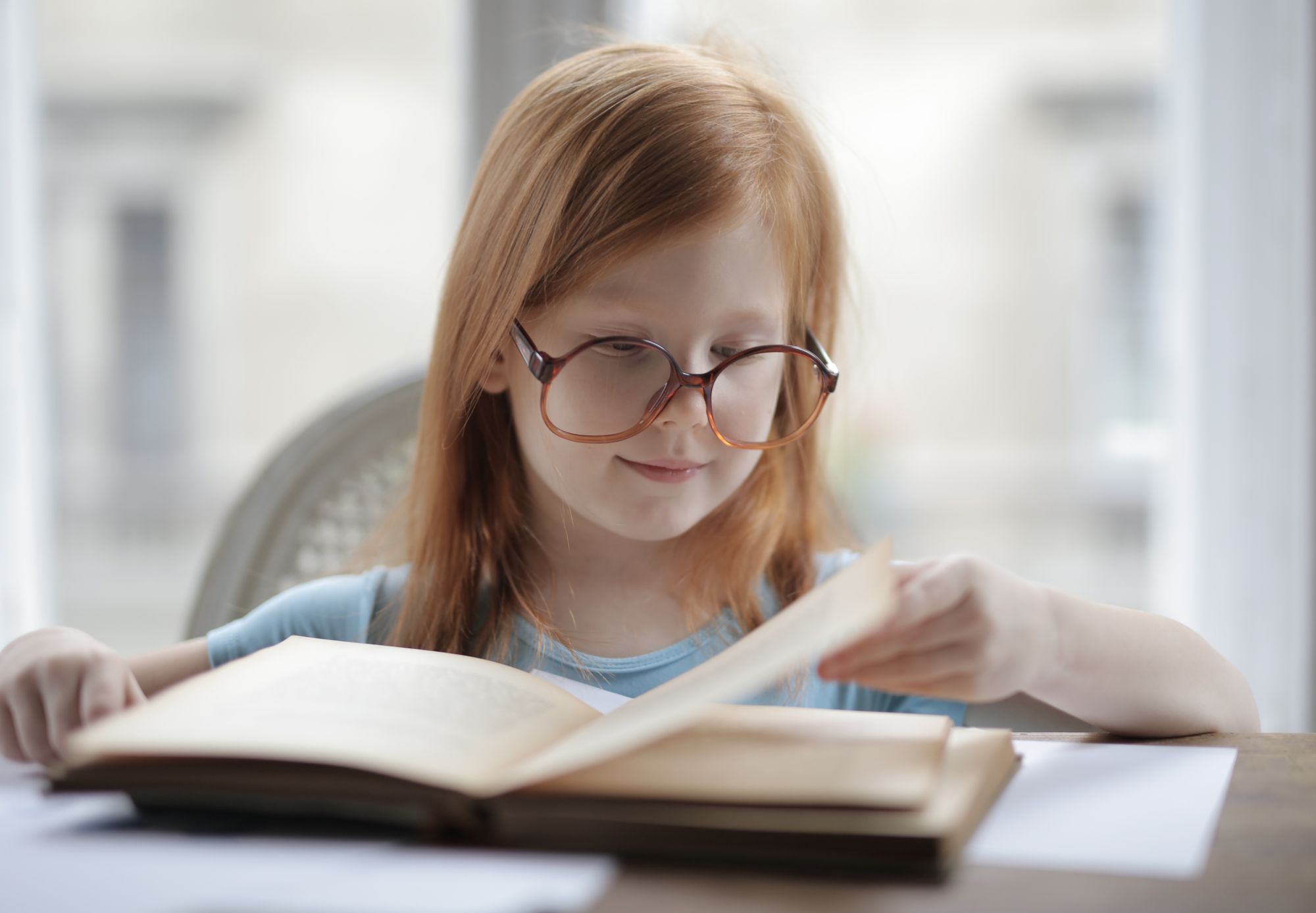 Meisje met bril leest geconcentreerd een boek