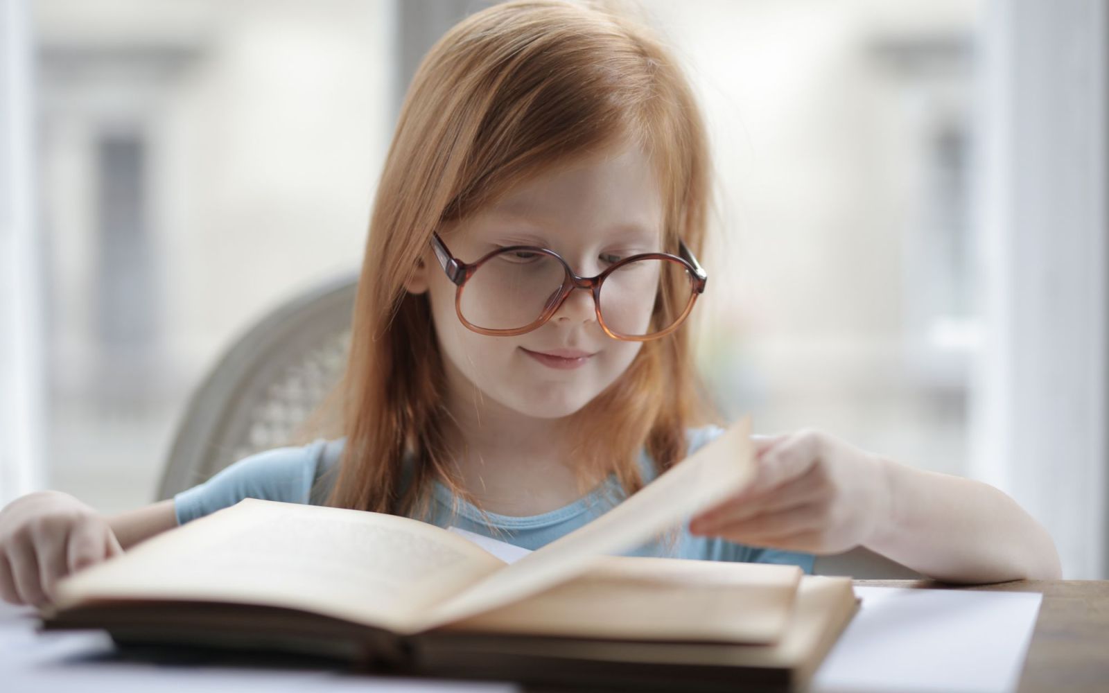 Meisje met bril leest geconcentreerd een boek